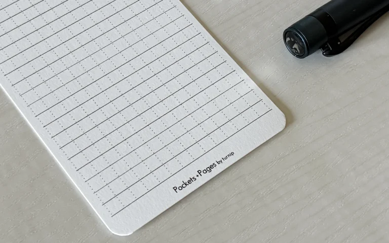 A lined index card with micro vertical dots with the branding "Pockets + Pages by turnip" on the bottom of the card.